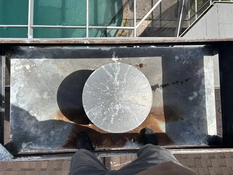Overhead view of person standing on concrete cylinder casting shadow below