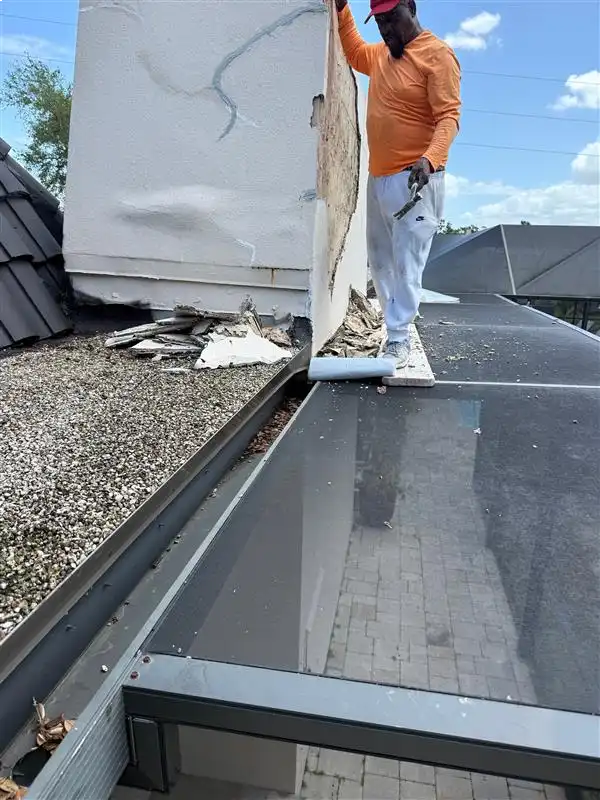 Roofer repairing damaged chimney flashing on residential flat roof extension