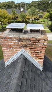 Brick chimney with two rectangular vent caps near palm trees on Anna Maria Island