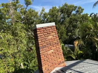 Tall brick chimney rising through a dense oak canopy on an Osprey, FL property